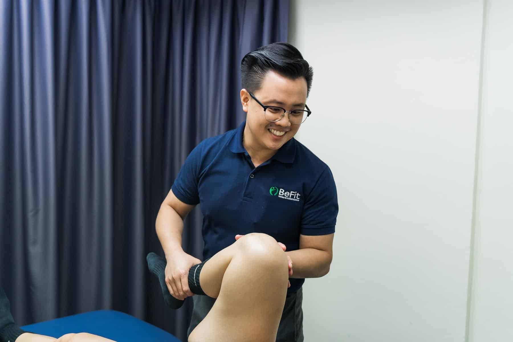 Professional physiotherapist performing knee examination and manual therapy on patient. Image shows hands-on treatment technique, knee assessment, joint palpation, and therapeutic intervention in clinical setting. Keywords: knee therapy, manual examination, physical assessment, rehabilitation, orthopedic treatment, patient care.