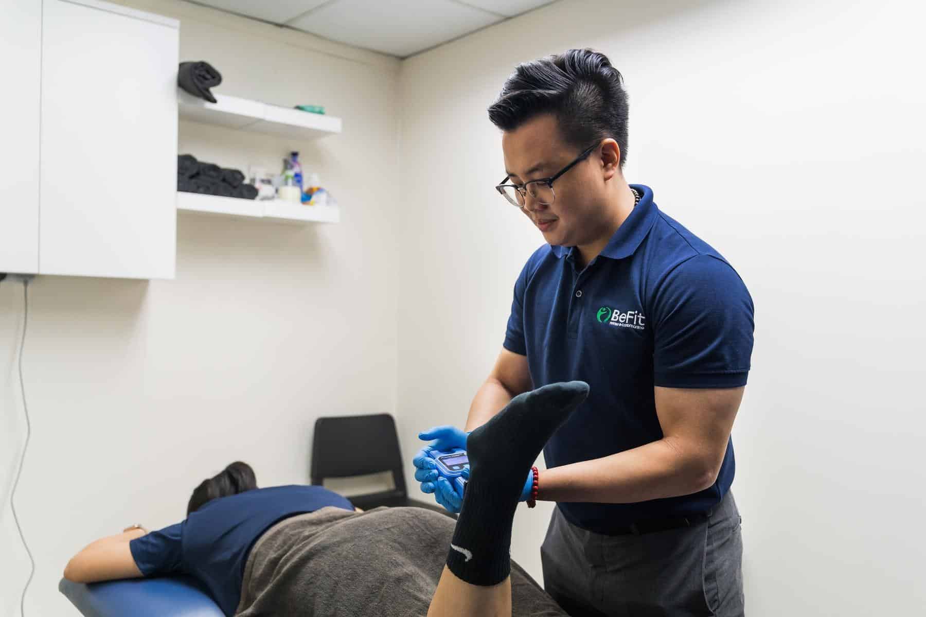 Therapist examining and assessing patient's leg with protective gloves and compression sleeve in clinical setting. Shows lower limb evaluation, ankle assessment, injury examination, and detailed patient assessment. Keywords: leg examination, ankle therapy, lower limb assessment, compression therapy, physical evaluation, clinical assessment.